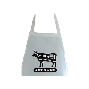 May include: White apron featuring a black silhouette of a cow with labelled cuts of meat. The text "ANY NAME" is printed below the cow.