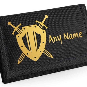 May include: Black trifold wallet with a gold shield and crossed swords design. The text "Any Name" is printed in gold on the front.
