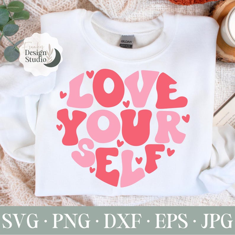 K&ouml;nnte beinhalten: Wei&szlig;er Pullover mit einem pinkfarbenen und roten Herzdesign, auf dem in einer Retro-Schrift "LOVE YOURSELF" steht.