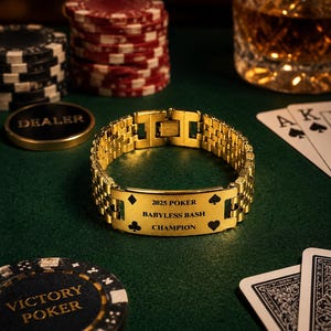 Puede incluir: Una pulsera dorada con la inscripci&oacute;n "2025 POKER BABYLESS BASH CHAMPION" se muestra sobre una superficie de fieltro verde. Fichas de p&oacute;quer, naipes y un vaso de l&iacute;quido &aacute;mbar est&aacute;n en el fondo. La pulsera tiene un dise&ntilde;o de eslabones.