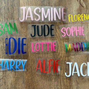 May include: A selection of heat transfer vinyl name decals in various colours, including pink, green, blue, and red. Names include Jasmine, Florence, Sam, Jude, Sophie, Edie, Lottie, Maddie, Harry, Alfie, and Jack.