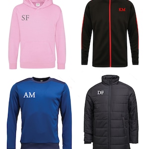 May include: Four different types of jackets with embroidered initials. The first jacket is pink with a hood and the initials "SF" embroidered on the front. The second jacket is black with red accents and the initials "KM" embroidered on the front. The third jacket is blue with a navy blue trim and the initials "AM" embroidered on the front. The fourth jacket is black with a quilted design and the initials "DF" embroidered on the front.