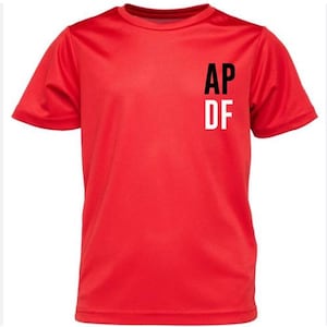 May include: A vibrant red short-sleeved t-shirt. The shirt displays the letters "AP" above "DF" in black and white on the upper left chest. The fabric appears to be smooth, possibly synthetic.