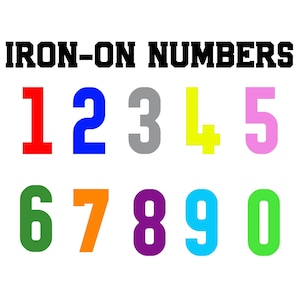 May include: Iron-on numbers in a variety of colours, including red, blue, grey, yellow, pink, green, orange, purple, cyan, and lime green. The numbers are arranged in two rows, with the numbers 1 through 5 in the top row and 6 through 0 in the bottom row.
