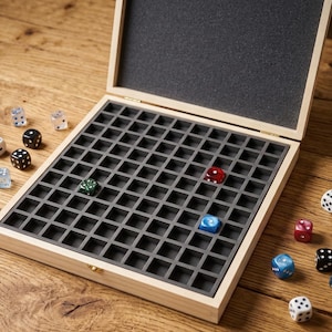 Peut inclure: Boîte de rangement en bois pour dés, avec un intérieur quadrillé, contenant plusieurs dés multicolores. La boîte est ouverte, révélant un intérieur gris foncé. Divers dés de couleurs variées, comme le rouge, le bleu et le noir, sont éparpillés autour de la boîte.