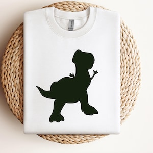 May include: White t-shirt with a black silhouette of a dinosaur.