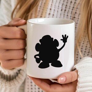 May include: White ceramic mug with a black silhouette of a cartoon character waving. The character has a round body and a single arm raised in a wave.