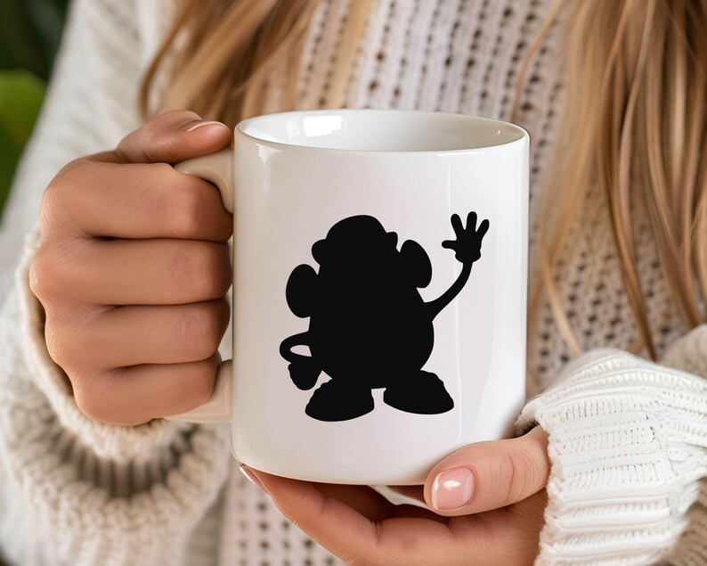 May include: White ceramic mug with a black silhouette of a cartoon character waving. The character has a round body and a single arm raised in a wave.