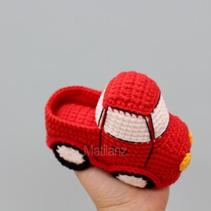 Handmade crocheted slipper shaped like a red car with white details and yellow accents.
