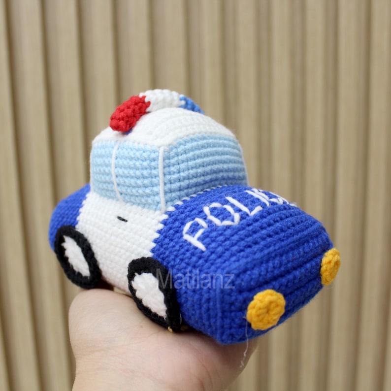 Handmade crocheted police car toy in blue, white, and red with yellow wheels and "POLICE" text on the side.