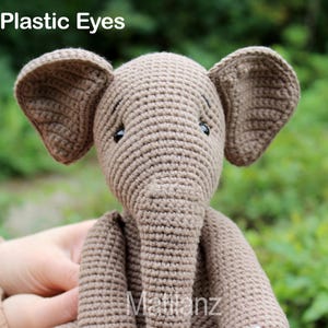 Handmade elephant-shaped toy crafted from beige crocheted cotton yarn, featuring floppy ears and plastic eyes.