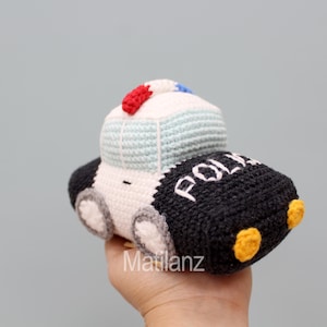 Handmade crocheted police car toy in black, white, blue, red, and yellow, featuring a classic car shape with wheels, lights, and "POLICE" lettering on the side.