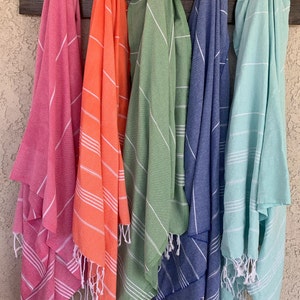 May include: Five striped towels hanging on hooks. The towels are in various colors, including pink, orange, green, blue, and light blue.
