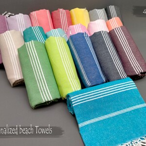 May include: A variety of colorful striped beach towels with white fringe. The towels are rolled up and arranged in a row. The text "40X70" is visible in the upper right corner of the image. The text "Personalized beach Towels" is visible in the lower left corner of the image.