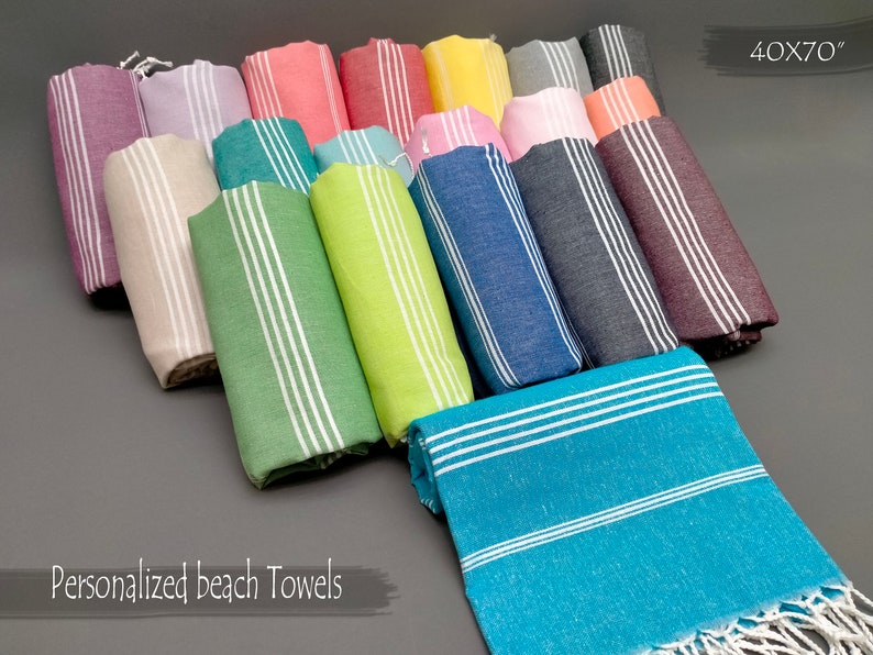 May include: A variety of colorful striped beach towels with white fringe. The towels are rolled up and arranged in a row. The text "40X70" is visible in the upper right corner of the image. The text "Personalized beach Towels" is visible in the lower left corner of the image.