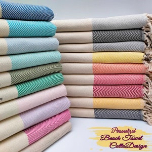 May include: A stack of colorful beach towels with a herringbone pattern. The towels come in various colors, including blue, green, pink, and yellow, with a white border and fringe. The text "Personalized Beach Towel Calla Design" is visible.