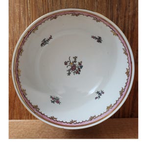 May include: White ceramic bowl with a pink and gold rim, adorned with floral patterns. The bowl features a scalloped edge and small floral clusters. A central floral design adds to the decorative appeal.