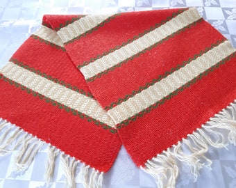 Puede incluir: Dos caminos de mesa tejidos a rayas rojas y blancas con detalles verdes y flecos blancos.