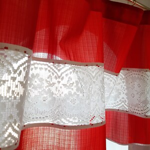 Puede incluir: Cortinas rojas y blancas con un ribete de encaje. Las cortinas están hechas de una tela transparente y tienen un borde fruncido.