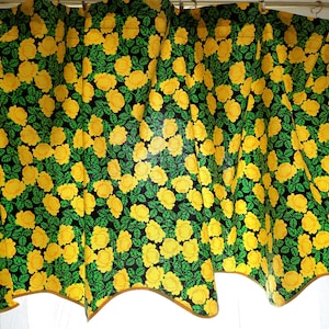 Puede incluir: Tela de estampado floral amarillo y verde con borde festoneado. La tela presenta un patrón repetitivo de rosas amarillas sobre un fondo verde oscuro.