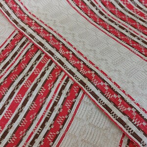 May include: Red and brown striped fabric with a white background. The fabric has a woven pattern.