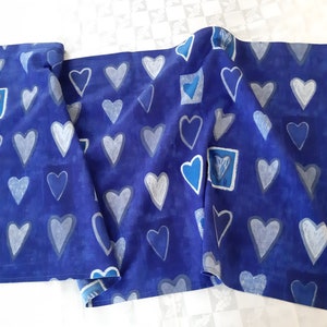 Puede incluir: Caminero de mesa de tela azul con un patrón de corazones blancos. Los corazones están delineados en blanco y tienen un centro azul.