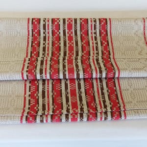 May include: A beige table runner with red and brown stripes and a geometric pattern.