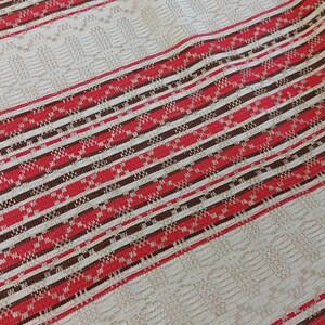 May include: Striped fabric with red, brown, and white woven stripes. The fabric has a textured pattern.