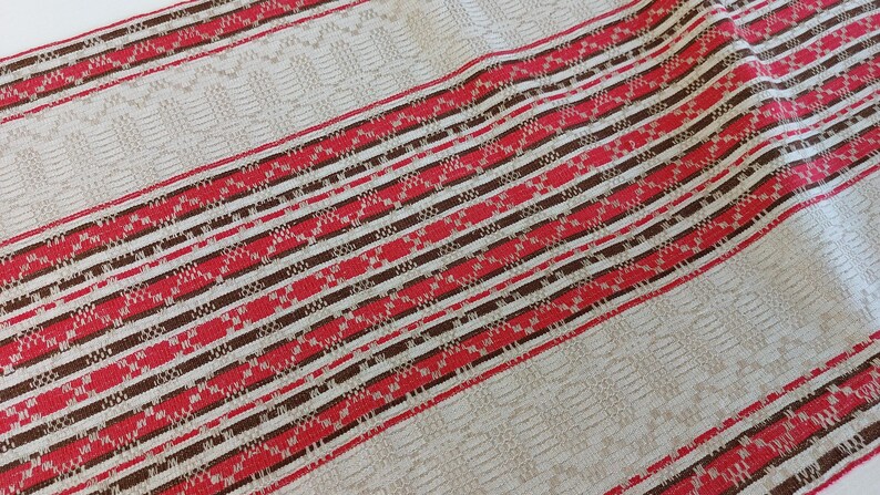 May include: Striped fabric with red, brown, and white woven stripes. The fabric has a textured pattern.