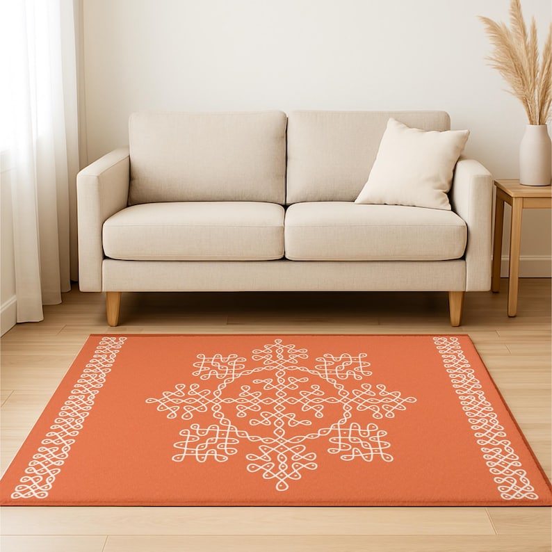 May include: An orange area rug with a white geometric design. The rug has a border of white geometric shapes.