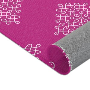 May include: A pink rug with a white geometric pattern. The rug is rolled up, showing the gray backing.