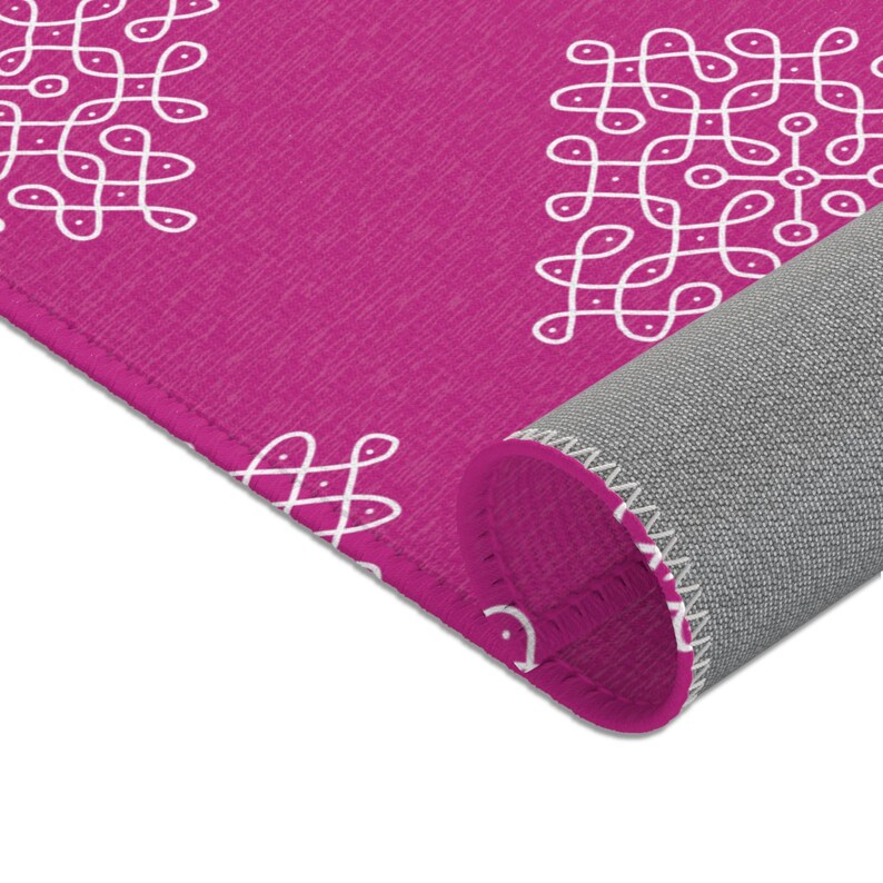 May include: A pink rug with a white geometric pattern. The rug is rolled up, showing the gray backing.