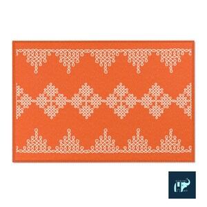 May include: Orange rug with a white geometric pattern. The pattern is made up of repeating knots and swirls. The rug has a stitched border.