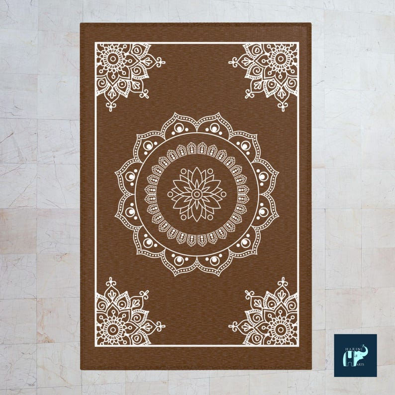 May include: A brown rectangular rug with a white mandala design. The mandala has a flower in the center and is surrounded by circles and dots.