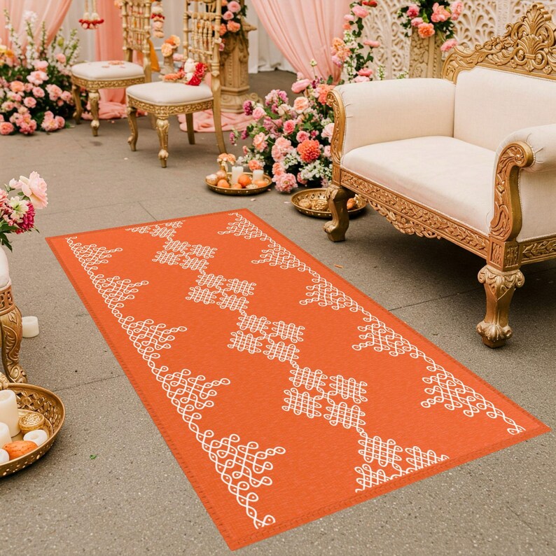 May include: An orange and white patterned runner rug with a traditional Indian design. The rug is laid out on a floor in front of two chairs and a couch.