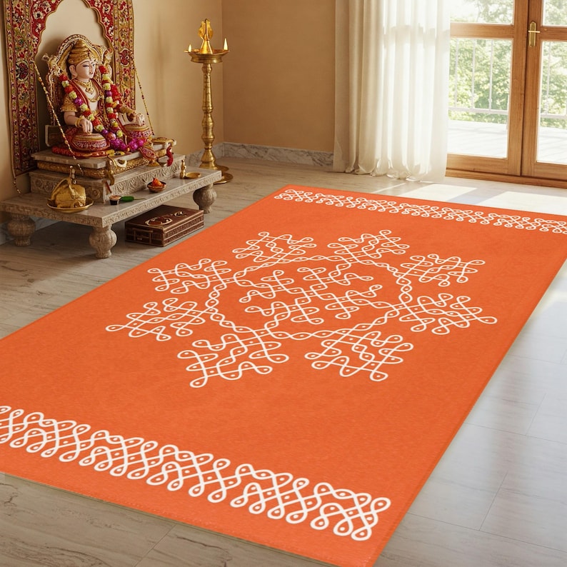 May include: Orange and white patterned rug with a traditional Indian design. The rug has a white border with a repeating pattern and a larger white design in the center.