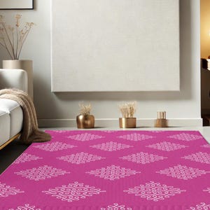 May include: A pink area rug with a white geometric pattern. The rug has a repeating pattern of white, intricate designs on a solid pink background.