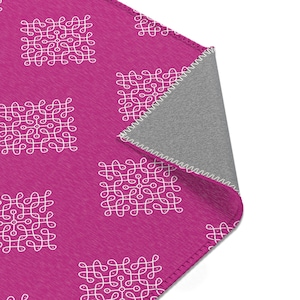 May include: A pink fleece blanket with a white geometric pattern. The blanket has a gray backing and is folded in half.