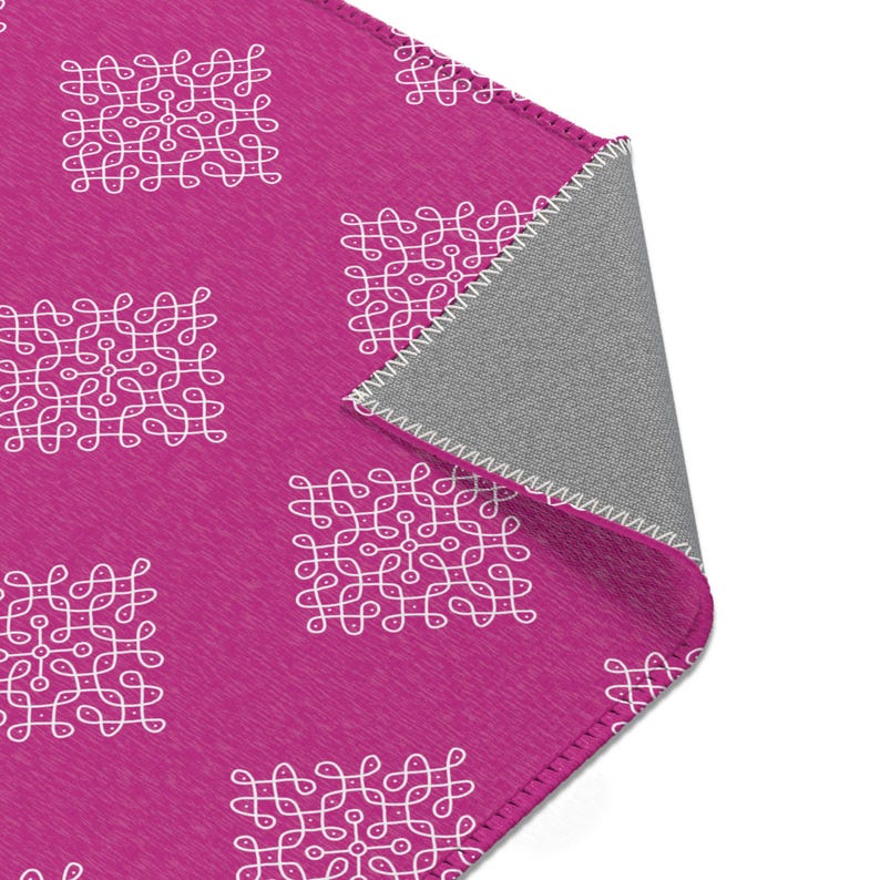 May include: A pink fleece blanket with a white geometric pattern. The blanket has a gray backing and is folded in half.