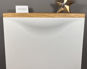 Könnte beinhalten: Ein weißer, an der Wand befestigter Schrank mit einer Holzplatte. Auf der rechten Seite des Schranks befindet sich eine goldfarbene sternförmige Dekoration. Auf der linken Seite des Schranks befindet sich eine kleine weiße Karte mit dem Text "HOLZEIT".