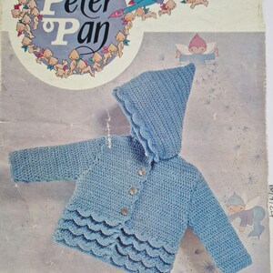 May include: A crochet pattern for a blue hooded jacket with a scalloped hem. The pattern is called "a Wendy crochet design" and is for a chest size of 18-20 inches. The pattern is from Double Knittings.