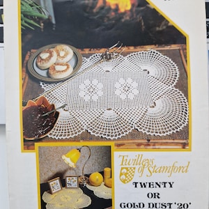 May include: A crochet pattern booklet with a white crocheted doily on a wooden table with a fireplace in the background. The booklet is titled "Twilleys of Stamford Twenty or Gold Dust '20' Home Crochet".