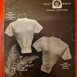 Può includere: Volantino di modelli di maglieria vintage con due maglioni a maglia a maniche corte. Il volantino è intitolato "Golly Wools Double Knitting" e include il testo "Ladies Quick-to-Knit Jumper" e "Economy Designs by Kay". Lo sfondo è nero e il volantino è in scala di grigi.