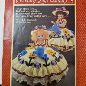 May include: A craft kit titled "Mary Quite Contrary" featuring instructions for a 10 1/2" pillow doll with a crocheted skirt and a 13" bed doll dress. The image shows two dolls with yellow crocheted skirts, floral accents, and hats.