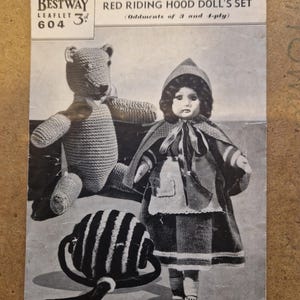 May include: Bestway leaflet 604 with a crochet pattern for a teddy bear, pram ball, and Red Riding Hood doll set. The image displays a knitted teddy bear, a striped pram ball, and a doll dressed as Red Riding Hood.