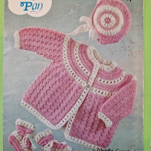 May include: A vintage crochet pattern for a baby set, including a pink and white jacket, bonnet, and booties. The pattern is from "Peter Pan" and a "Wendy Crochet" design. The set is made in 4-ply yarn.