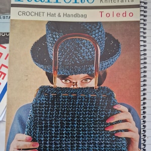 Puede incluir: Un folleto vintage de patrones de crochet para un sombrero y un bolso. La portada presenta a una mujer con un sombrero y un bolso de crochet azul, con el título "Raffene Crochet Hat & Handbag Toledo" y el número "No. C101 6d. Knitcrafts".