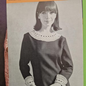 May include: Vintage black and white image of a woman wearing a dark dress with a white crochet collar and cuffs. The image is from a "COATS Mercer-Crochet Design" leaflet. The leaflet's text includes "LEAFLET 1022" and "PRICE 6d."
