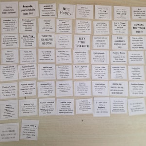 Peut inclure: Un ensemble de petites cartes carrées blanches avec du texte noir. Les cartes présentent des affirmations positives et des citations de motivation. Certaines cartes affichent des phrases comme « Bee Happy! » et « Always fry your best! ». Les cartes sont disposées sur une surface claire.