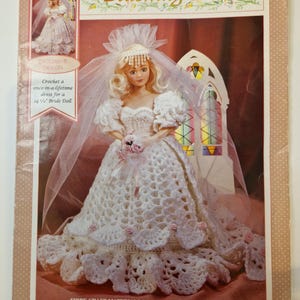 May include: A crochet pattern for a "Blushing Bride" doll, designed for a 36.8 cm doll. The cover shows a doll in a white crochet wedding dress with a veil and bouquet. The pattern is from Fibre-Craft Materials Corp.